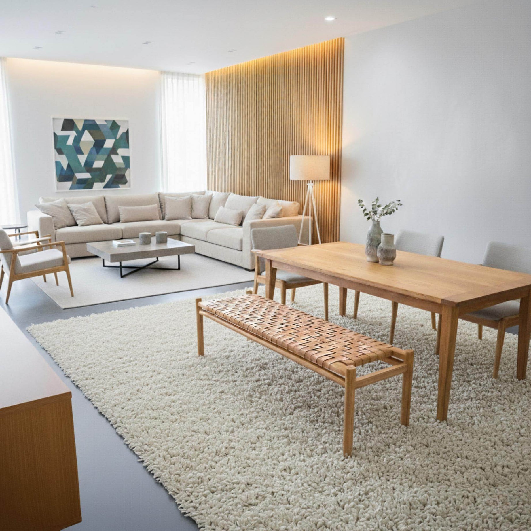 Modern living room with a sectional sofa, coffee table, leather bench and dining set.