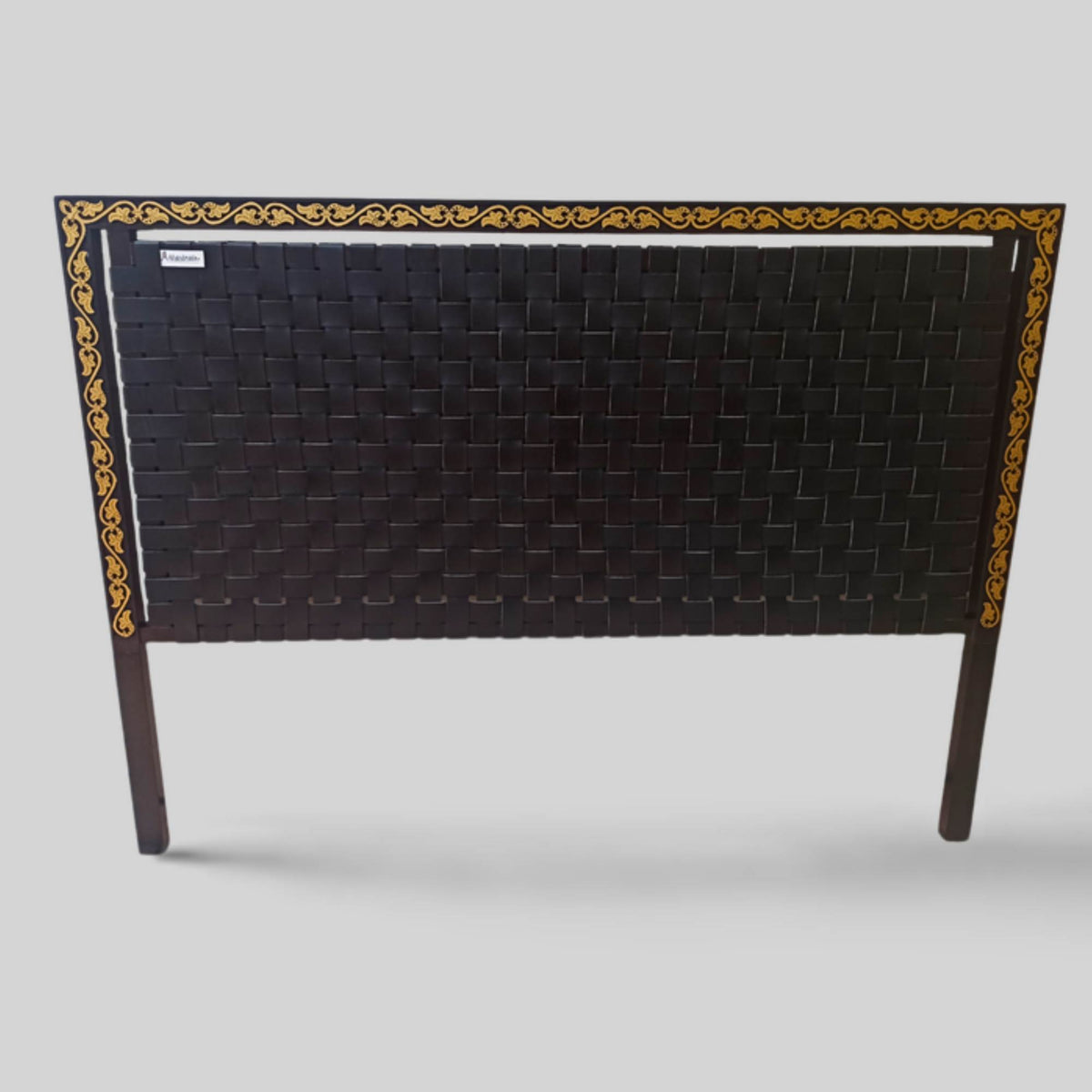 Close-up of handwoven leather strap across solid teak headboard