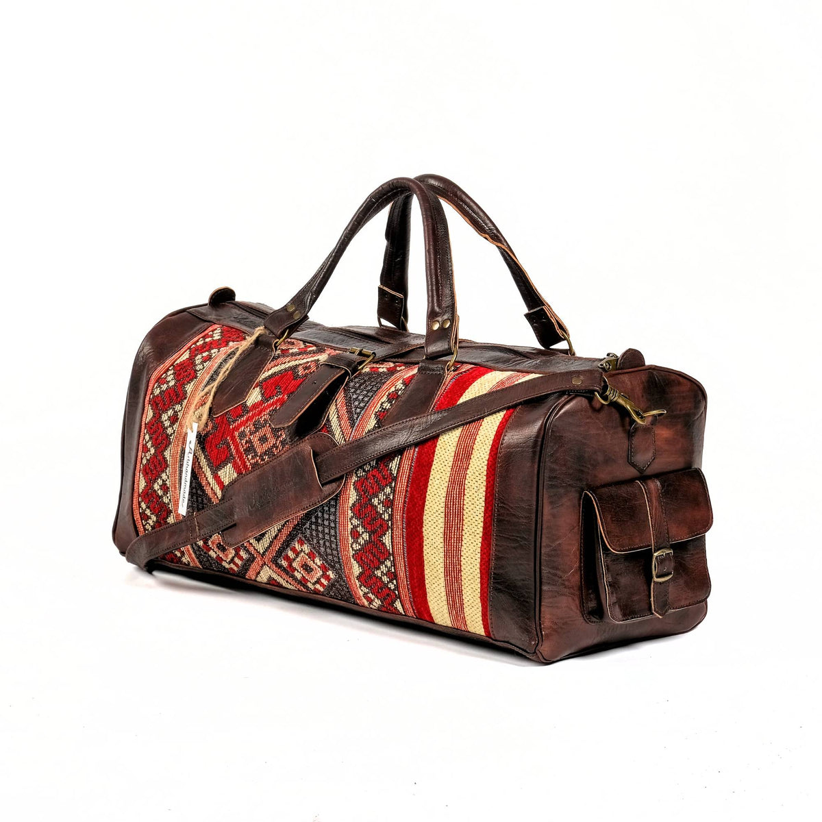 A handcrafted dark brown leather duffel bag with a kilim design, featuring a shoulder strap and side pockets.