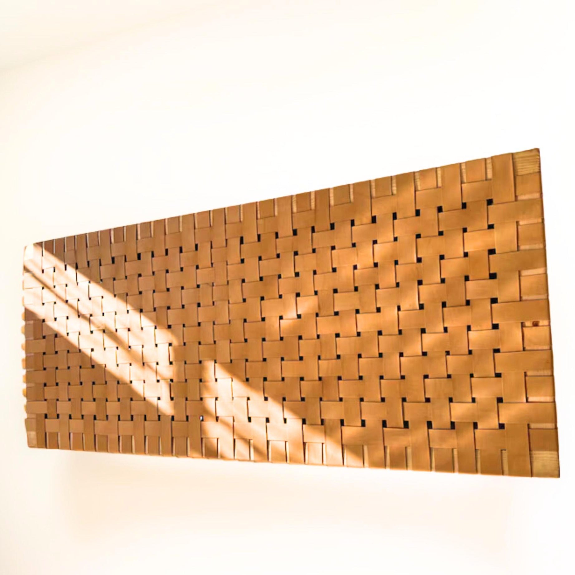 Side profile of a contemporary strap woven leather queen  Hanging headboard highlighting its dynamic structure