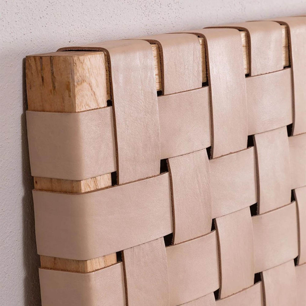 Close-up of handwoven leather strap across solid teak headboard